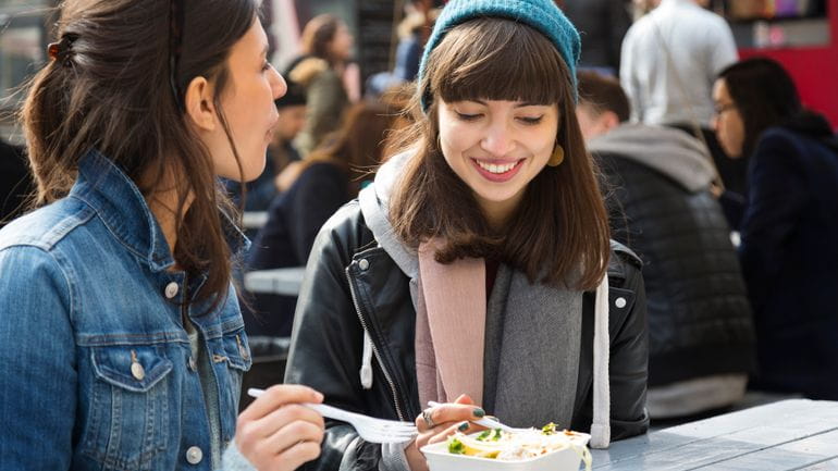 dwie dziewczyny jedzące posiłek na zewnątrz